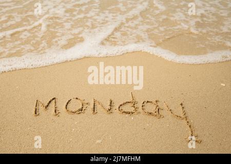 Lundi - tirage sur le sable de la plage avec une vague de claquement douce. Banque D'Images