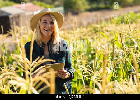 Portrait d'une femme cacuasienne moyenne souriante, adulte, portant un chapeau avec une tablette numérique dans la ferme Banque D'Images