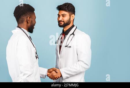 portrait de przloseup d'un professionnel de la santé intellectuel avec un laque blanc discutant des résultats avec un jeune médecin sur fond bleu Banque D'Images