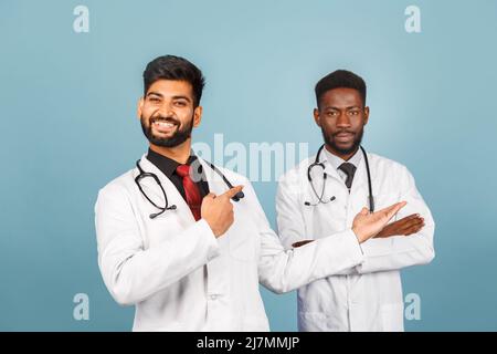 portrait de przloseup d'un professionnel de la santé intellectuel avec un laque blanc discutant des résultats avec un jeune médecin sur fond bleu Banque D'Images