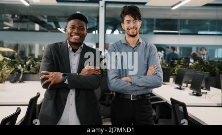 Deux collègues d'affaires multiraciaux souriant divers collègues jeune arabe homme d'affaires africain homme d'affaires homme d'affaires debout à l'intérieur se posant ensemble Banque D'Images
