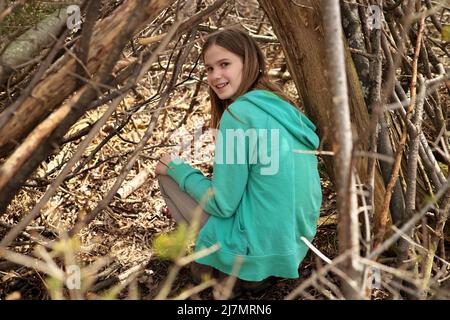 Jeune fille adolescente dehors dans la forêt avec maigre-à l'arbre fort treehouse maison d'arbre qu'elle a construit Banque D'Images