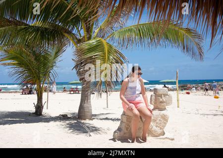 Jeune femme assise sur la statue maya, El Pescador Marisqueria & Bar, Playa Chen Rio, Cozumel, Quintana Roo, Mexique Banque D'Images