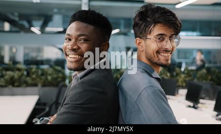 Portrait deux collègues hommes multinationaux hommes Africain arabe responsable indien posant dans une société de bureau se tenant debout les uns contre les autres partenariat Banque D'Images