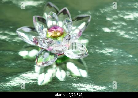 Lotus cristal sur fond vert brillant avec réflexion de lumière. Symbole de chakra anahata. Ésotérique, énergie reiki, méditation, guérison spirituelle. Banque D'Images