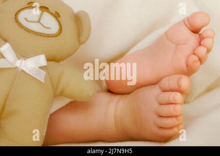 Pieds de bébé avec ours en peluche et couverture Banque D'Images