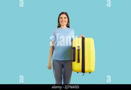 La femme heureuse qui va en vacances d'été tient sa valise jaune et souriante Banque D'Images