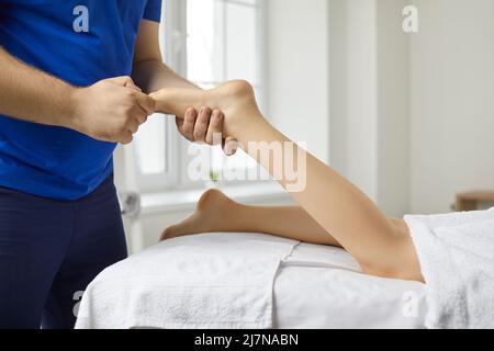 Le masseur thérapeute masculin exécute l'acupression des jambes de la jeune femme dans le centre de bien-être moderne. Banque D'Images