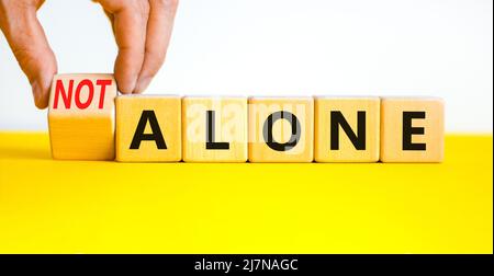 Vous n'êtes pas seul symbole. L'homme d'affaires tourne des cubes en bois et change les mots de concept seul à pas seul. Magnifique fond blanc. Business, support a Banque D'Images