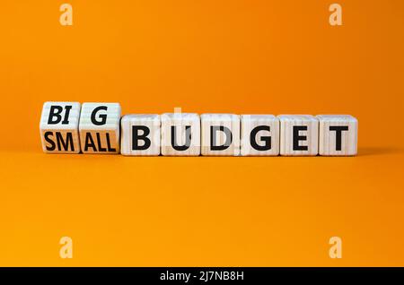 Symbole petit ou grand budget. Tourné cubes en bois et changé de concept mots petit budget à grand budget. Magnifique table orange fond orange, copie s Banque D'Images