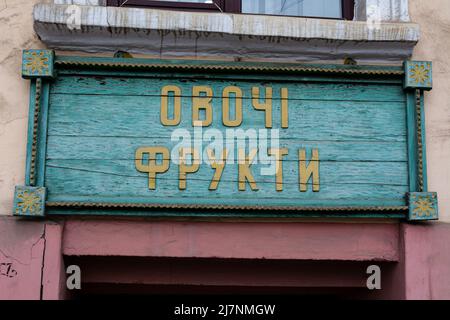 Ancienne assiette de la boutique avec l'inscription légumes et fruits en ukrainien. Peinture décolorée et fissurée sur la plaque, lettrage jaune et un g Banque D'Images