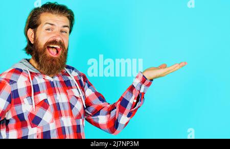 Joyeux barbu homme dans une chemise à carreaux présentant le produit tient quelque chose sur la paume. Mouvement de main de spectacle masculin. Banque D'Images