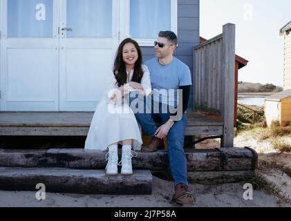un beau couple de courses mixtes s'est assis sur la plage dans une cabane de plage en été Banque D'Images
