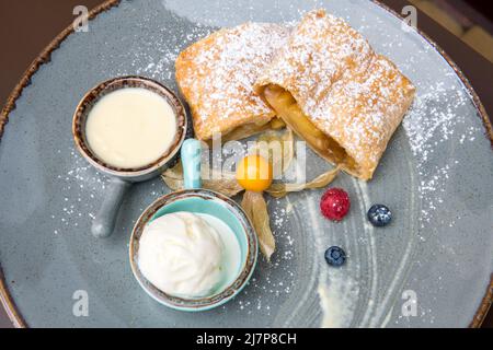 Strudel aux pommes au lait condensé, crème glacée, fraises fraîches Banque D'Images