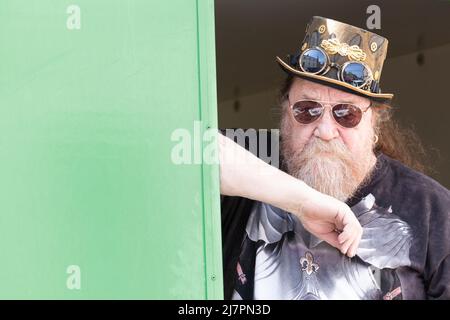 Barbu steampunk top chapeau homme dans des lunettes de soleil avec un regard sérieux sur son visage à la foire de rue Banque D'Images