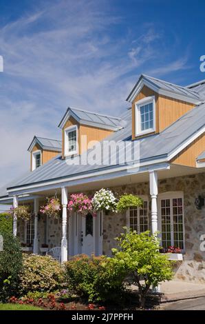 Réplique de l'ancienne maison en pierre de campagne de style cottage Canadiana 1800s avec garniture blanche et toit en tôle d'argent en été. Banque D'Images