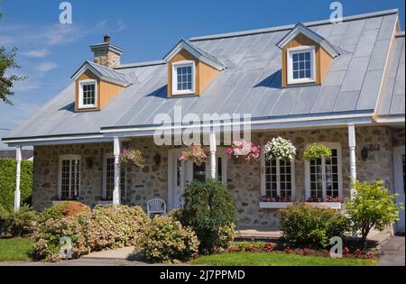 Réplique de l'ancienne maison en pierre de campagne de style cottage Canadiana 1800s avec garniture blanche et toit en tôle d'argent en été. Banque D'Images