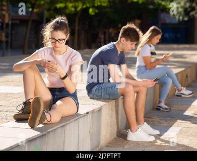 Adolescents avec des téléphones absorbés dans la communication en ligne Banque D'Images