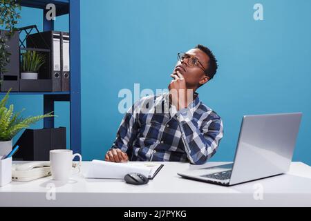 Smart look pensive jeune homme adulte pensant au plan de gestion d'entreprise et la stratégie de marketing. Personne d'affaires réfléchie et contemplative dans l'espace de travail de bureau reflétant profondément. Banque D'Images