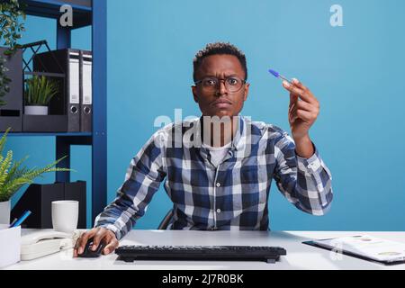 POV de incertain suspect administrateur de bureau ayant le stylo à la main regardant mal à l'écran d'ordinateur. Conseiller financier douteux confus analysant les statistiques financières du projet. Banque D'Images