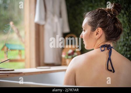 Femme dans le bain à remous appréciant le parfum de l'encens Banque D'Images