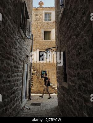 Homme marchant dans une petite rue avec des bâtiments en pierre dans la vieille ville de Budva, Monténégro Banque D'Images