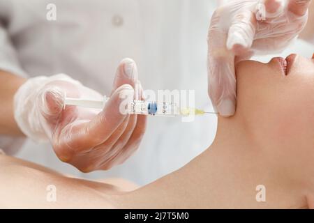 Le cosmétologue effectue la procédure de soulèvement du menton en injectant des injections de beauté. Médecin injectant de l'acide hyaluronique dans le ching d'une femme en tant que visage Banque D'Images