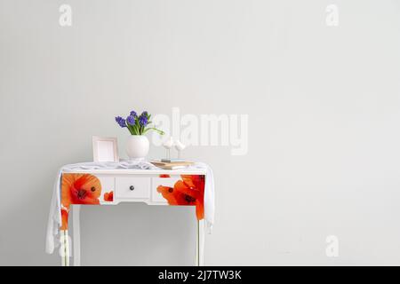 Table élégante avec fleurs en jacinthe fraîches dans un vase près du mur lumineux dans la chambre Banque D'Images
