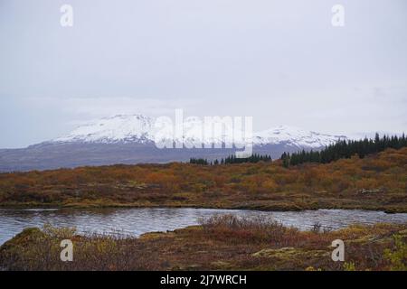 Magnifique paysage avec lac, forêt d'automne et montagnes enneigées tout en trekking dans le parc national de Thingvellir Banque D'Images