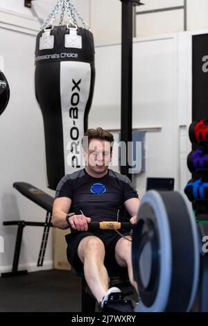Ipswich Suffolk UK avril 03 2022: Un jeune homme en forme et en bonne santé utilisant une machine à ramer dans une petite salle de sport Banque D'Images