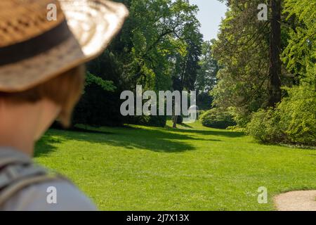 Femme aux cheveux bruns, t-shirt gris et chapeau de paille regardant le temple de Freudschaftstempel à Staatspark Fürstenlager, vue arrière, Auerbach, Bensheim, Ger Banque D'Images