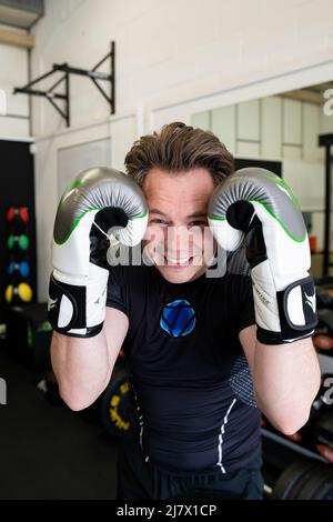 Ipswich Suffolk UK avril 03 2022 : un jeune homme en forme tenant un garde-boxe tout en portant des gants de boxe. Il sourit et regarde la caméra Banque D'Images