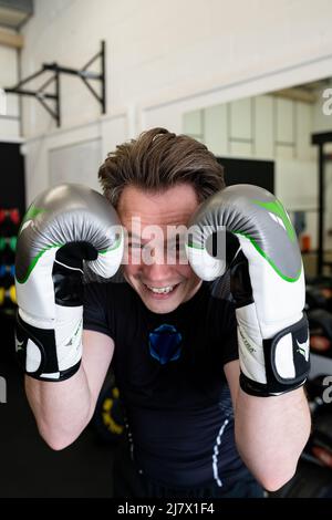Ipswich Suffolk UK avril 03 2022 : un jeune homme en forme tenant un garde-boxe tout en portant des gants de boxe. Il sourit et regarde la caméra Banque D'Images
