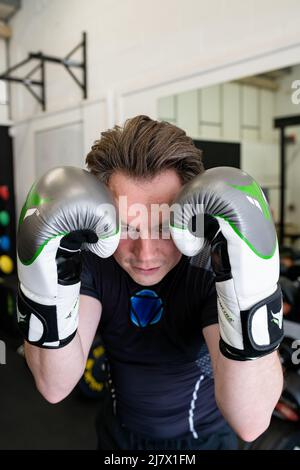 Ipswich Suffolk UK avril 03 2022 : un jeune homme en forme tenant un garde-boxe tout en portant des gants de boxe. Il sourit et regarde la caméra Banque D'Images