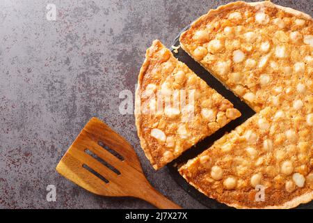 Petit gâteau doré avec noix et crème anglaise en gros plan sur une table en ardoise. Vue horizontale du dessus Banque D'Images