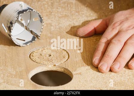 Travailleur avec fraise en action à l'atelier. Menuisier faisant des trous dans la planche de bois. BRICOLAGE Banque D'Images