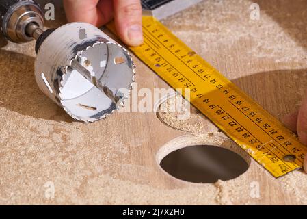 Travailleur avec fraise en action à l'atelier. Menuisier faisant des trous dans la planche de bois. BRICOLAGE Banque D'Images