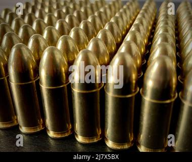 Bouquet de munitions en laiton brillant de 9 mm sur un bureau en bois sombre Banque D'Images