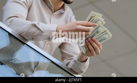 Gros plan des mains de sexe masculin comptant les billets de dollars à l'extérieur. Homme d'affaires tenant compte de l'argent comptant dans le bureau. Calcul de l'argent. Salaire du patron de l'employé Banque D'Images