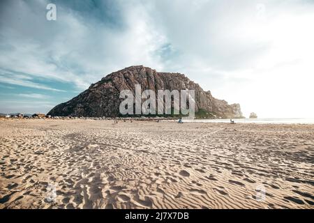 Morro Rock Beach au coucher du soleil en Californie avec un grand rocher au loin Banque D'Images