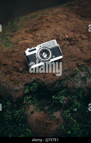 appareil photo argent vintage avec cuir noir sur un rocher dans la jungle Banque D'Images