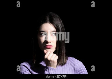 femme de brunette pensive avec fond noir Banque D'Images