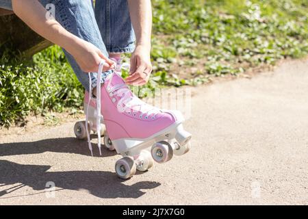 jambes d'une femme qui noue des patins à roulettes roses Banque D'Images