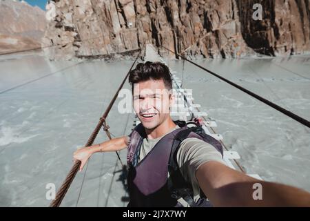 Voyageur sur un dangereux pont suspendu connu sous le nom de Hussani à Hunza Pakistan Banque D'Images