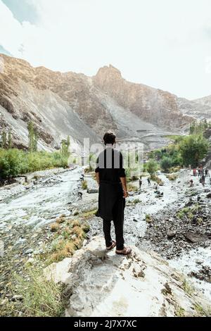 Jeune homme adulte debout dans un traditionnel shalwar kameez noir à Manthokha Waterfall Banque D'Images