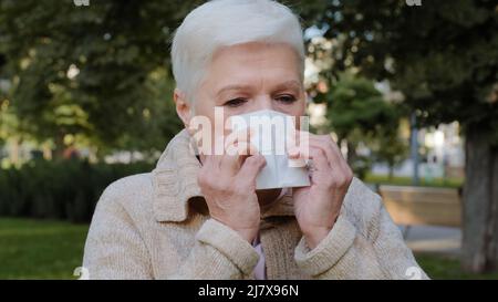 Une femme d'âge moyen allergique se sent mal à avoir le symptôme de la grippe, une femme âgée malade tient des éternuements de tissu a eu de la fièvre attrapée du froid soufflant nez dedans Banque D'Images