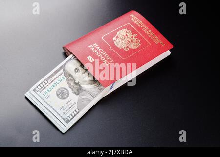 Passeport international russe avec dollars américains insérés sur fond noir. Banque D'Images