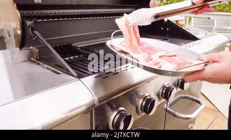 Cuisson de tranches de bacon sur un barbecue à gaz extérieur. Banque D'Images