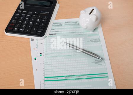 Gros plan d'une déclaration d'impôt avec une calculatrice, un stylo et une banque de porc Banque D'Images