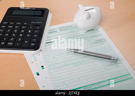 Gros plan d'une déclaration d'impôt avec une calculatrice, un stylo et une banque de porc Banque D'Images